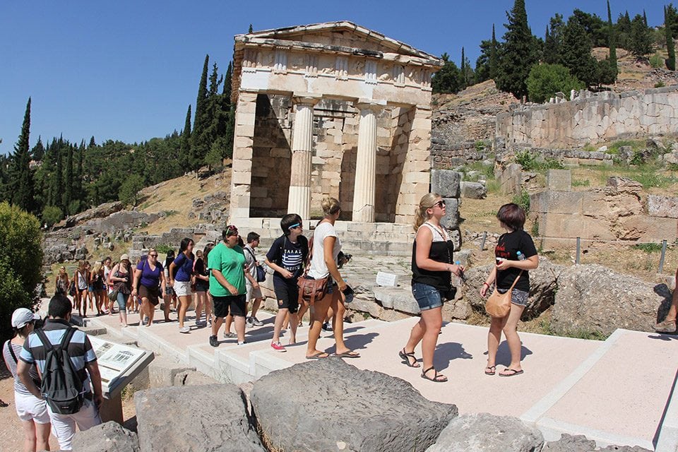 a group of people walk through greek ruins