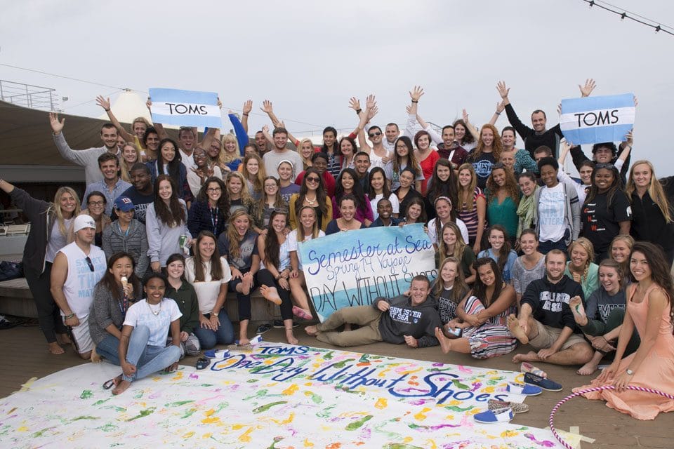 large group of students pose together with signs about shoe donations